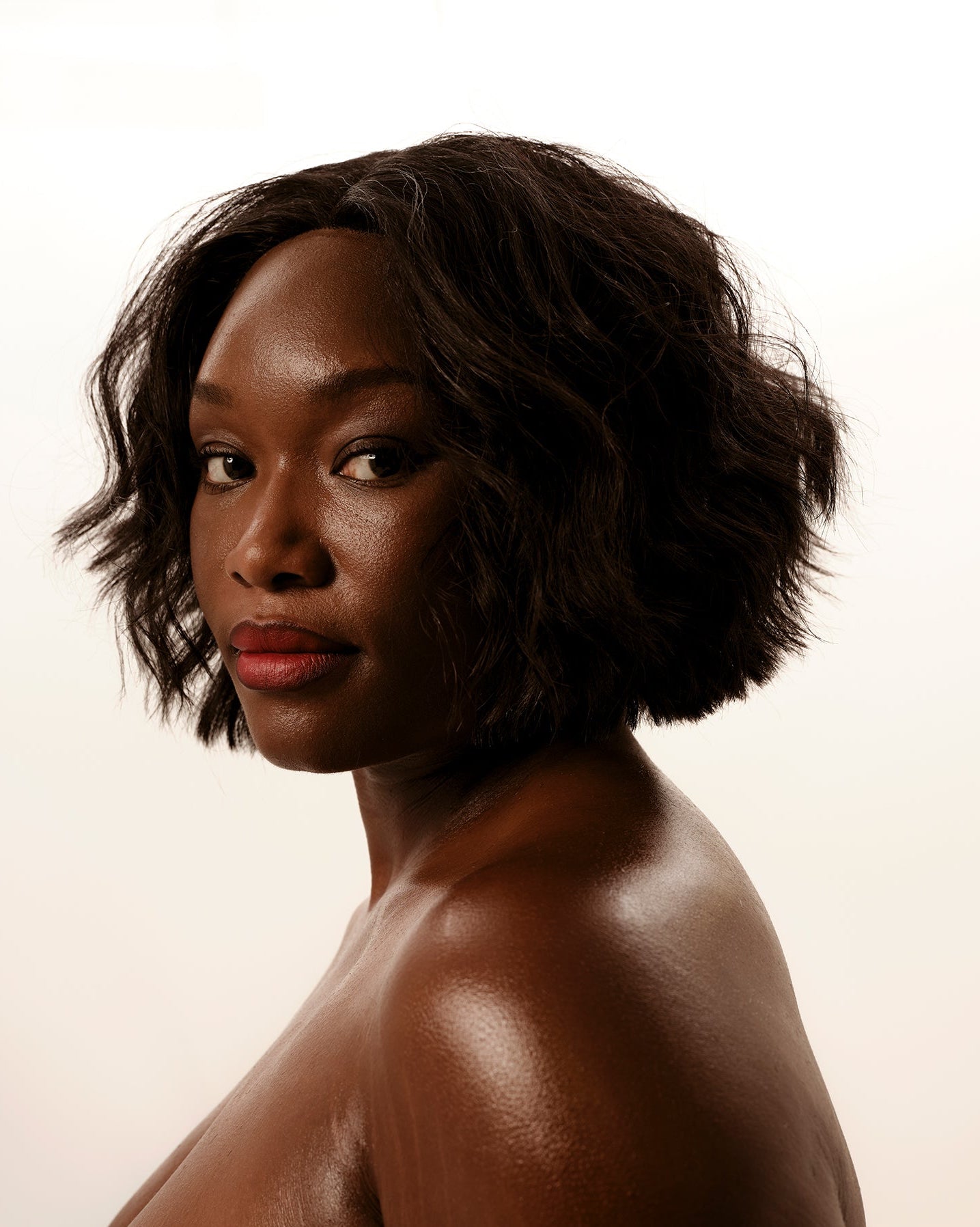 Woman with short, wavy hair against a plain background